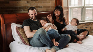 a family of four laughing and cuddling on a bed