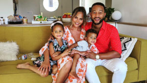 Chrissy Teigen and John Legend posing on the couch with their two children