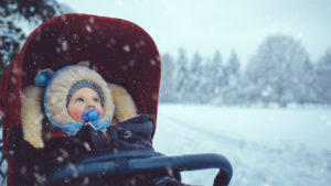 baby sitting in stroller on a snowy day