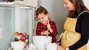 pregnant mom and preschooler baking in festive kitchen