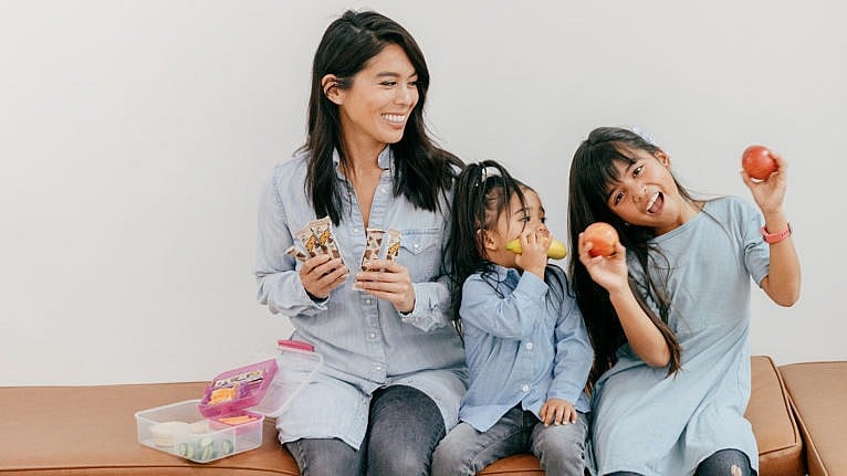 Trisha Enriquez and her two daughters holding snacks