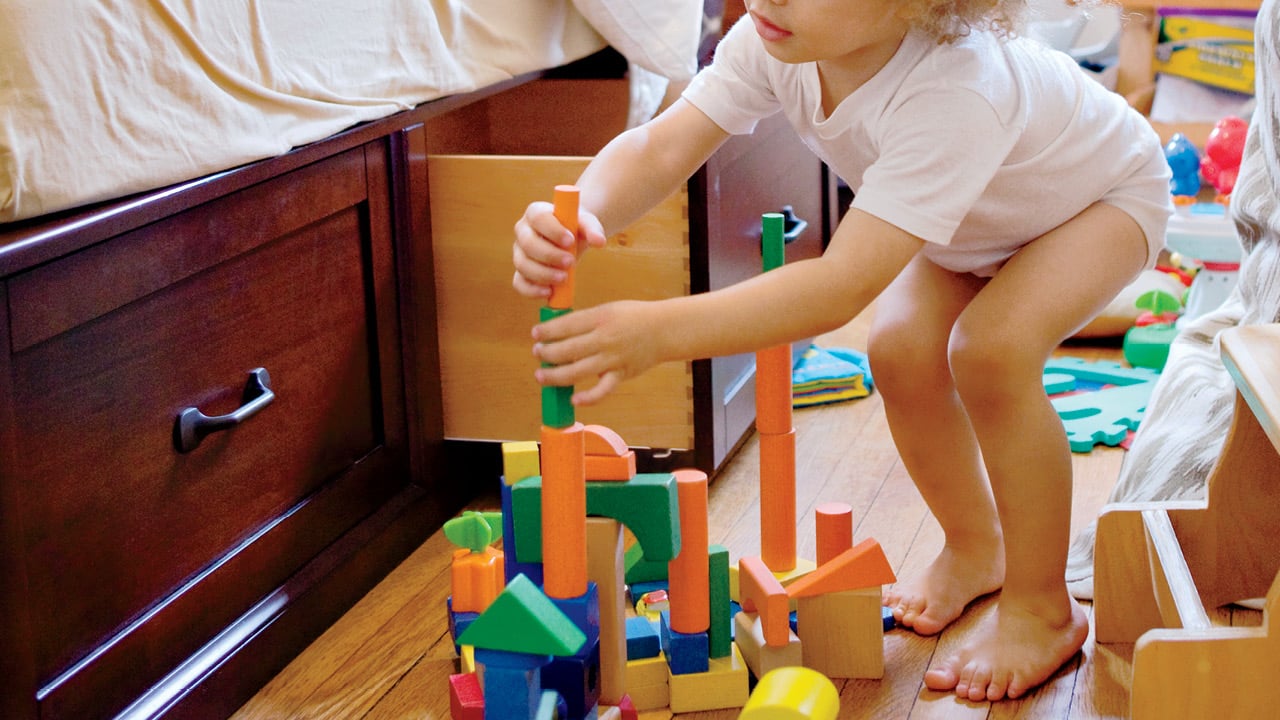 a toddler out of their bed playing with blocks for a story on milestone development