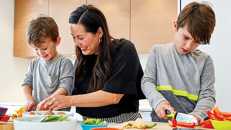 A mom and her two kids prepare a meal in the kitchen together