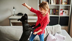 Photo of a little kid playing with a puppy on the couch