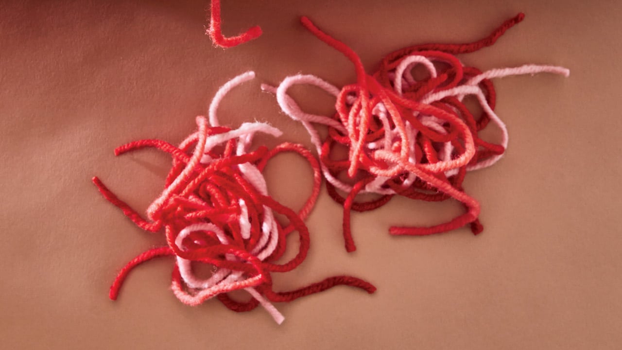 Photo of two piles of unraveled yarn in red and pink tones