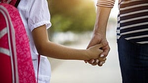 A photo from behind of a mother and daughter holding hands for a story on parenting with an anxiety disorder