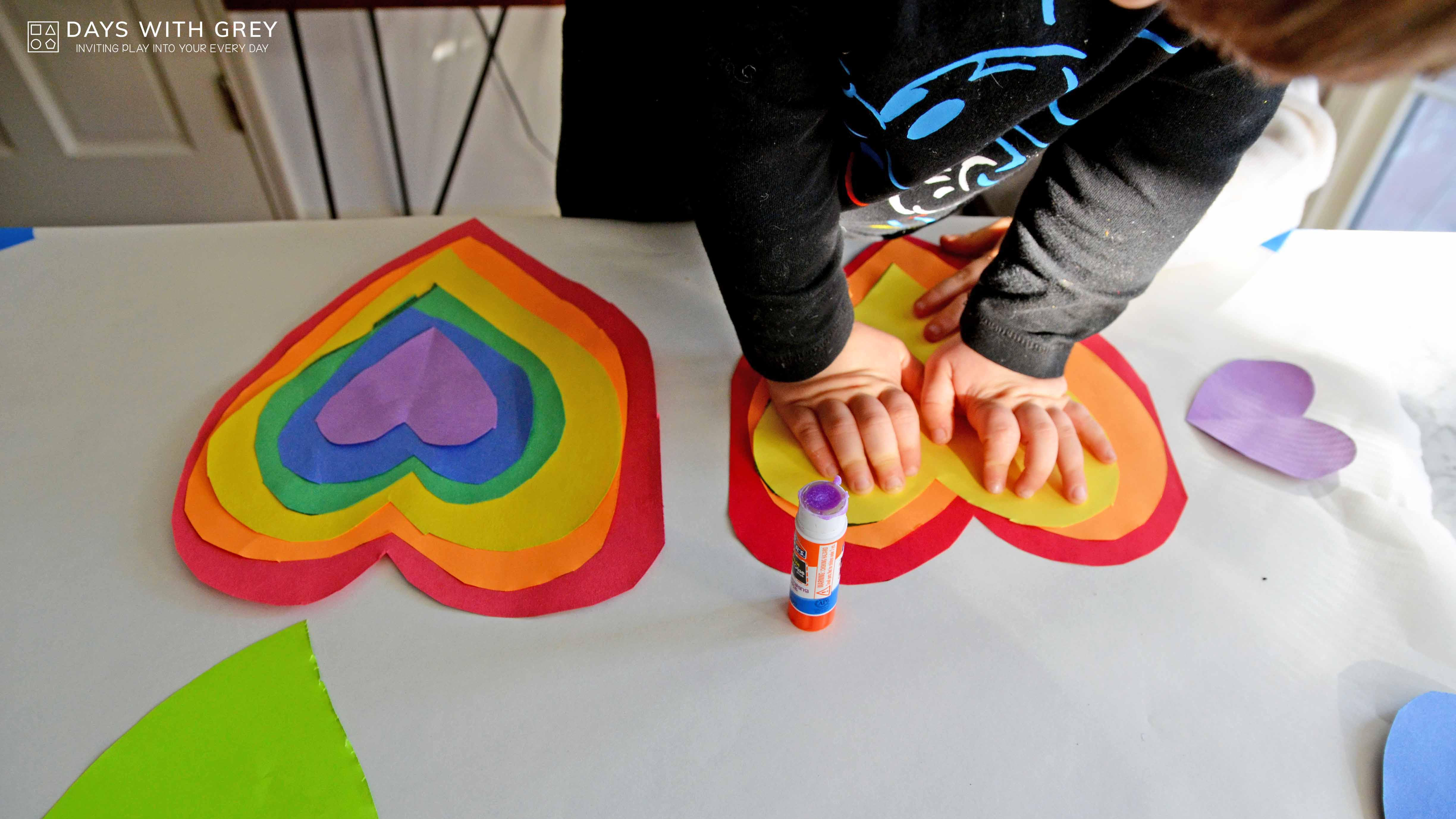 kids hands making a rainbow stack of hearts with paper cutouts for a story on toddler activities you can set up the night before
