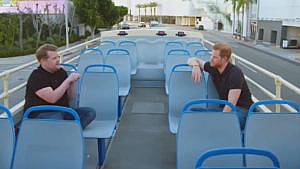 Still of James Corden and Prince Harry talking while riding through Los Angeles on a double decker bus