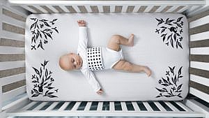 baby laying in crib with patterned sheet