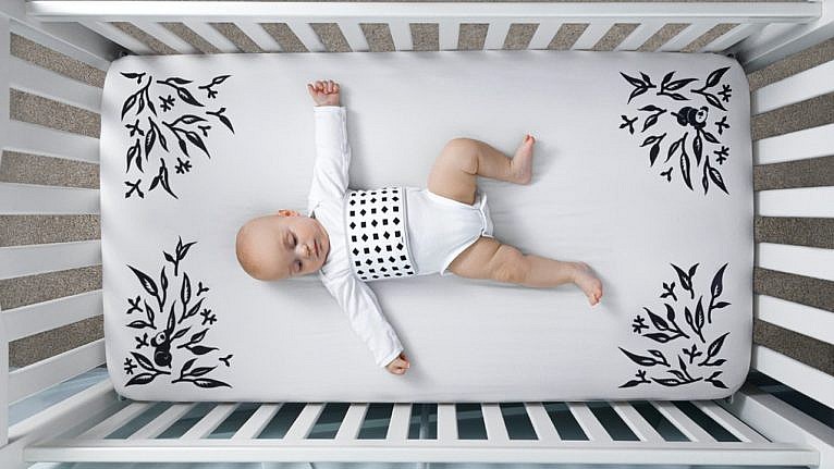 baby laying in crib with patterned sheet