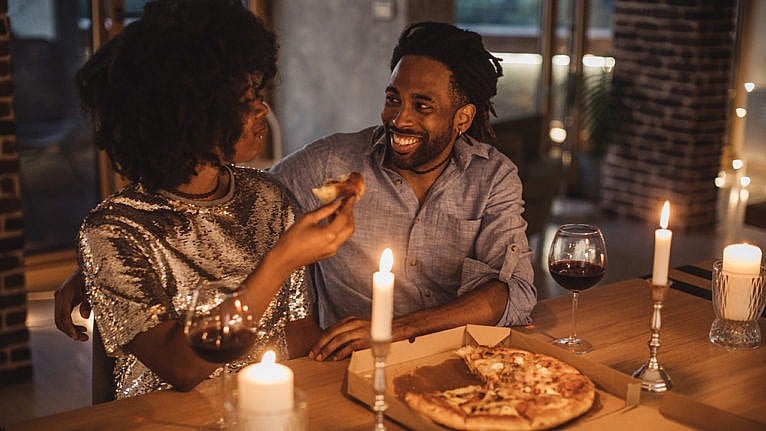A couple sharing a pizza by candlelight and with wine
