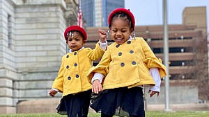 Photo of two sisters dressed up in yellow coats and red headbands to honour Amanda Gorman for Black History Month