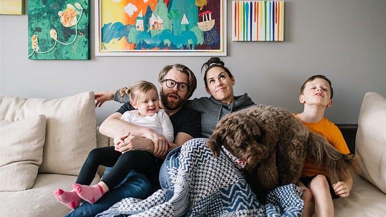 a man and woman piled onto the couch with their son, daughter and dog for a story on disability parenting during the pandemic