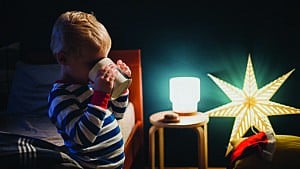 A kid drinking water in his bedroom with lots of night lights on for a story about sleep training six-year-olds