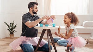 a man in a tutu having a tea party with his daughter who is also in a tutu