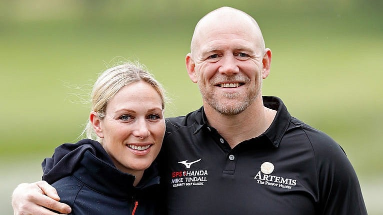 zara and mike tindall pose smiling wearing windbreakers on a green field
