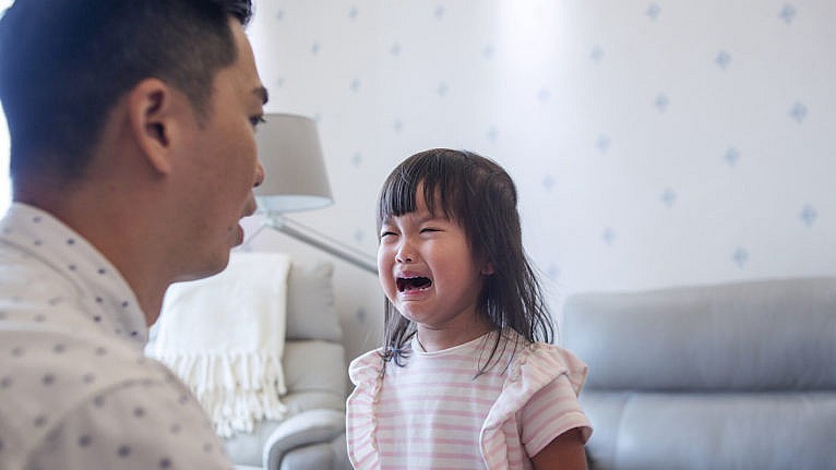 Close up of Asian father consoling cure crying daughter in living room of the house.