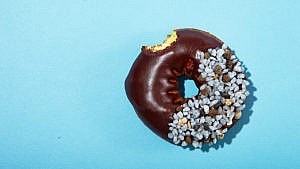 Photo of a chocolate donut with a small kid-sized bite taken out of it