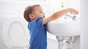 A little boy washing his hands after going to the bathroom for a story on bathroom independence