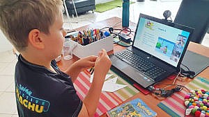 photo of a kid in front of a laptop participating in a Pokémon themed lesson through the Outschool platform