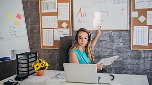 Photo of a teacher pointing to a white board while doing online school for kids