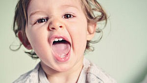 Photo of a toddler with their mouth wide open showing off their teeth