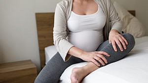 A pregnant woman holds her leg in pain for a story on blood clots during pregnancy