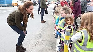 Duchess Kate Middleton bending down to talk to a group of kids
