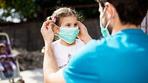 dad putting a mask on his daughter