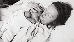 black and white photo of mom holding newborn baby in hospital bed