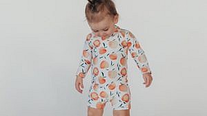 baby wearing a white sunsuit with peaches