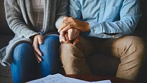 sitting couple holds hands in front of a table of papers