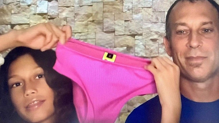 Ruby holds up a pair of pink bikini bottoms with her dad beside her