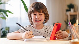 young boy crying while doing remote learning