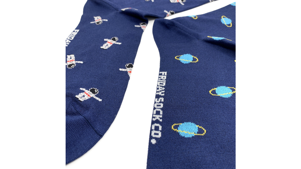 Mismatched pair of blue space-themed socks, one with Saturn print and the other with an astronaut design 