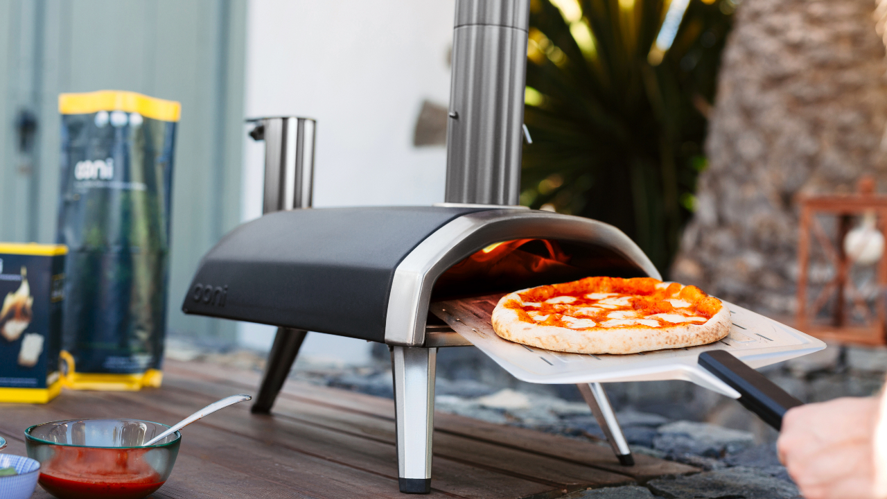 Outdoor pizza oven with baked pizza being taken out of it
