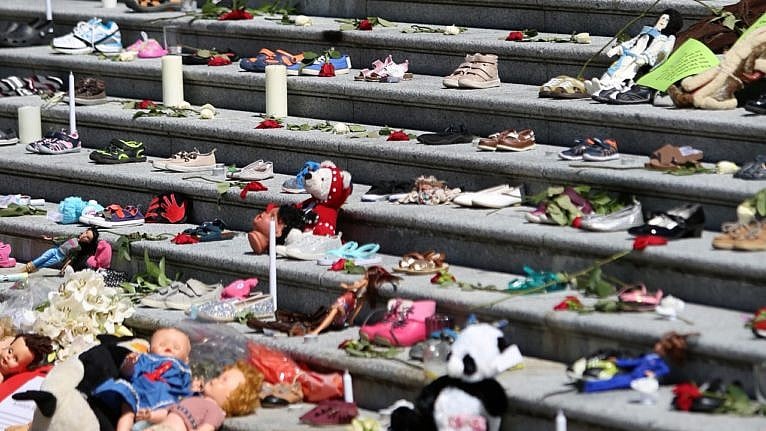 a variety of shoes, candles, and child dolls placed on stone steps