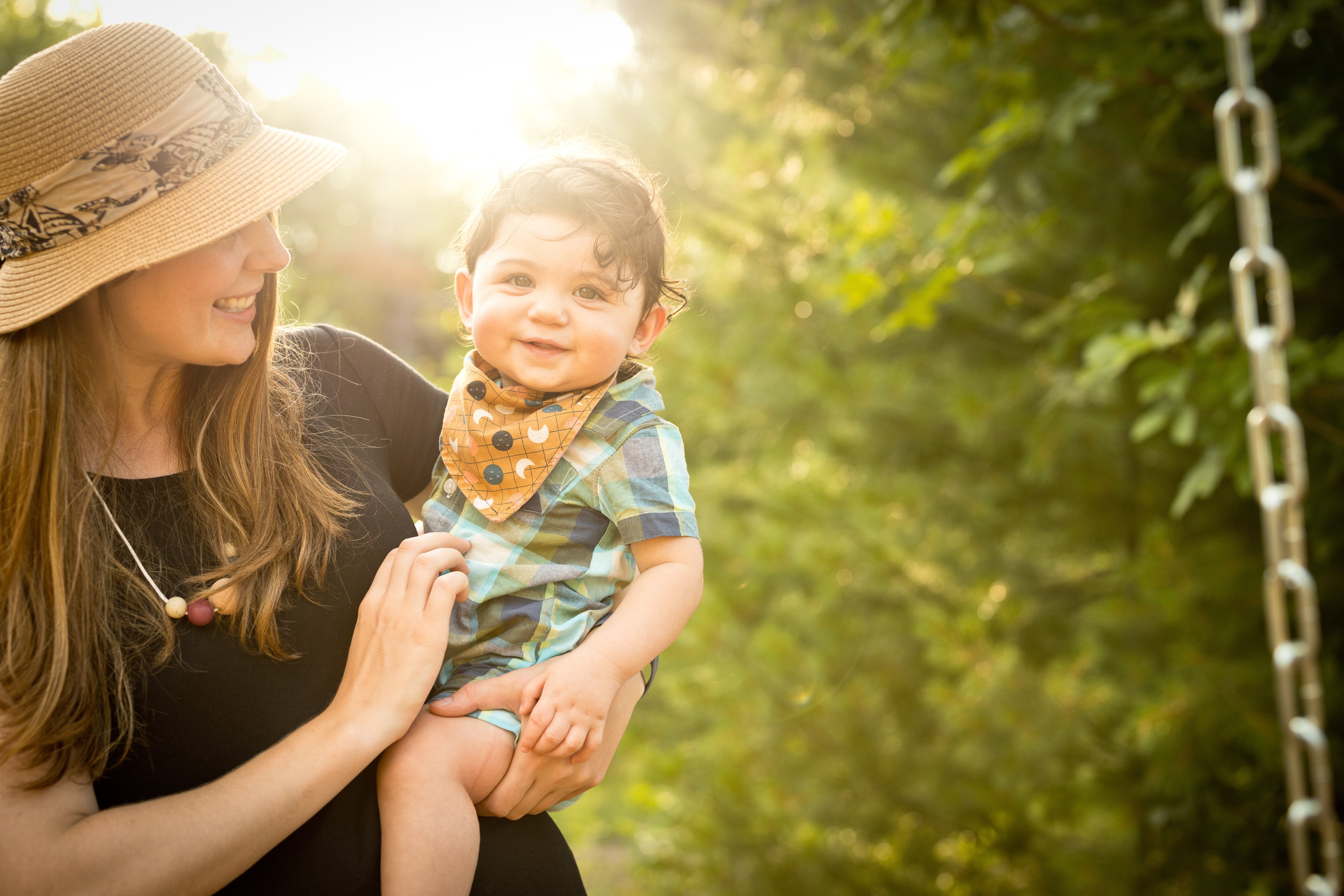 photo of a mother in a sun hat holding her baby surrounded by trees
