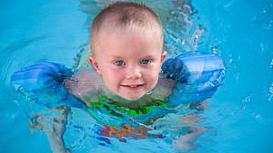 a young child in a pool wearing a puddle jumper