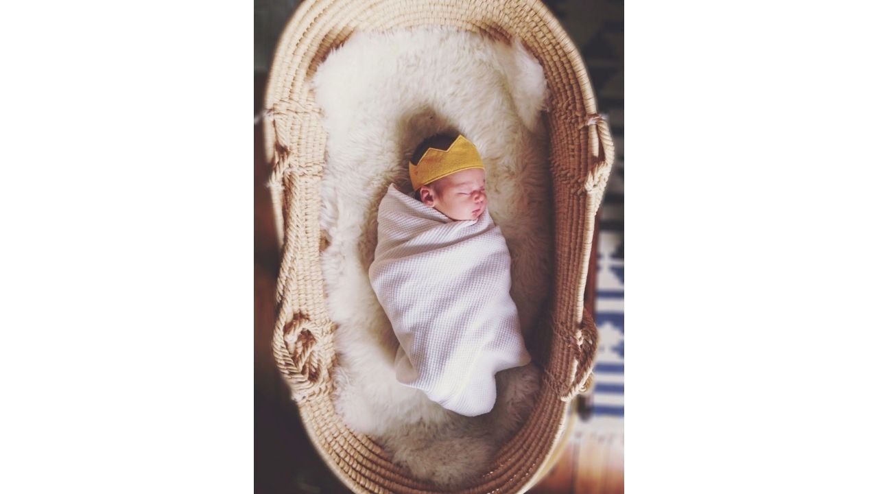 swaddled baby lying in a moses basket