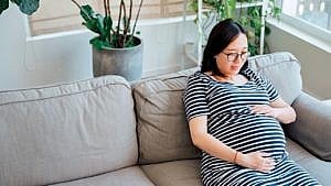 A woman sitting on the couch holding her baby bump