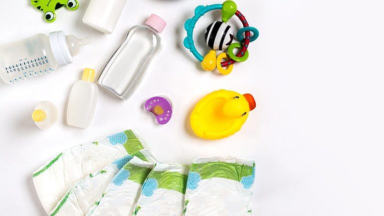 various baby products laid out on a white surface including diapers baby oil and a yellow rubber ducky