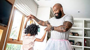 a dad in a tutu dances with his daughter