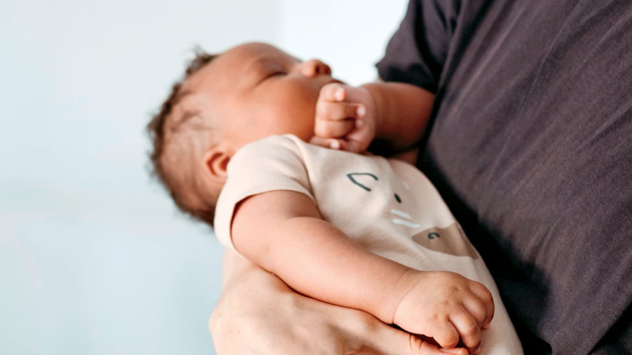 Photo of a newborn sleeping while being held by an adult