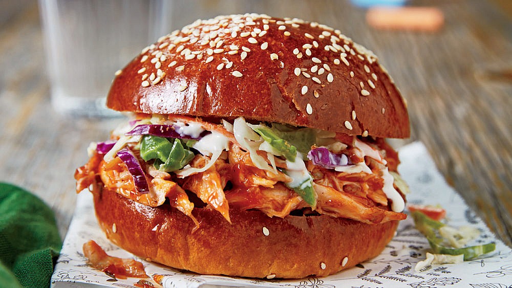 Photo of a pulled chicken sandwich with coleslaw on a sesame seed bun