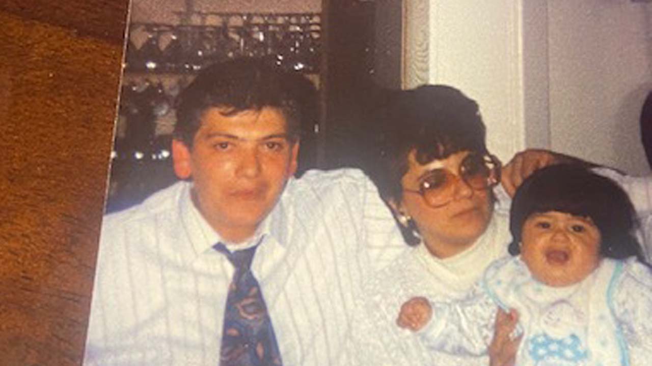 Photo of Melissa as a child, her adopted mother in the middle wearing a white shirt and her adopted father on the left in a button up shirt and tie