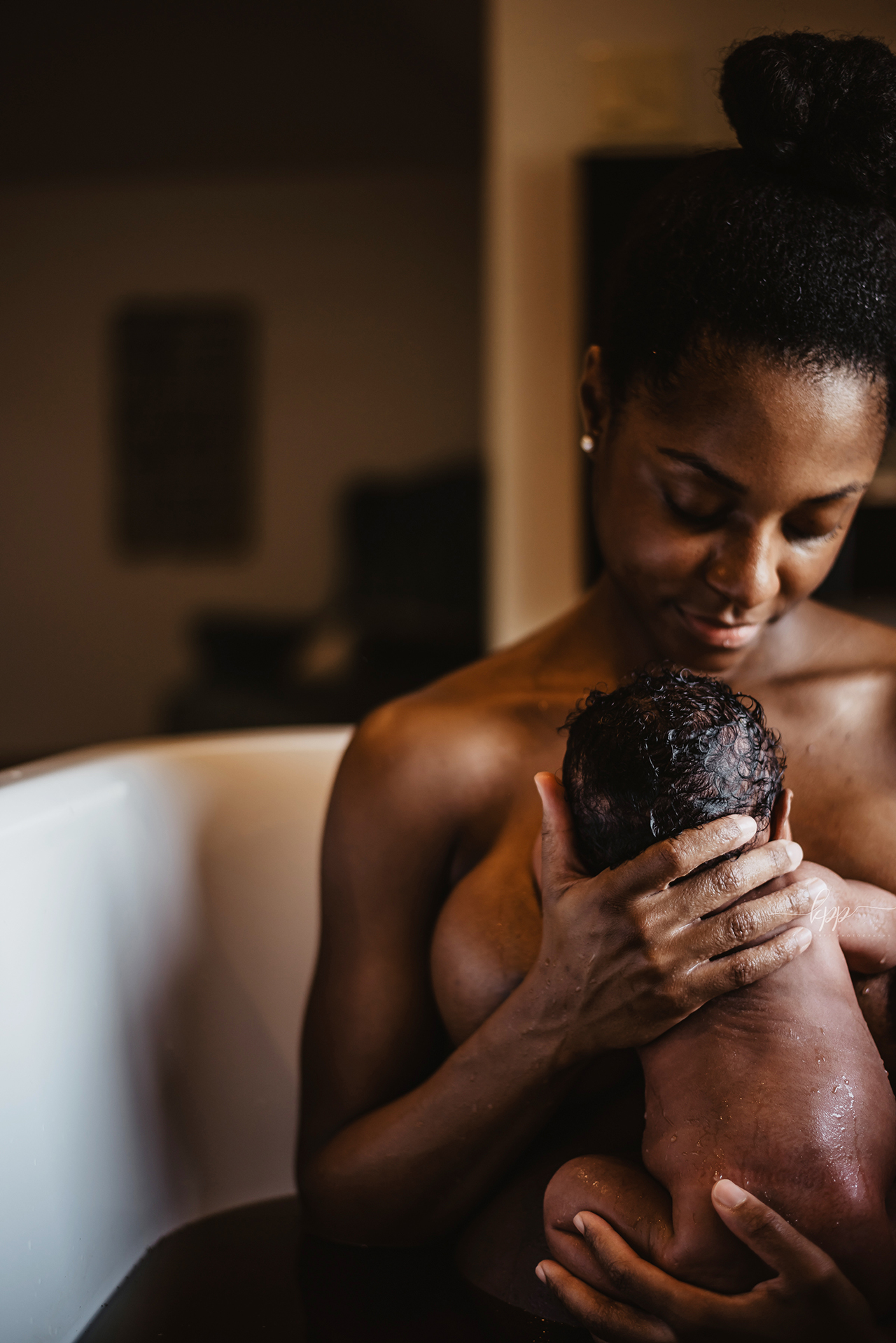 A woman bathes with her newborn baby from the life after birth coffee table book about the postpartum experience