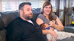 Photo of a couple and their newborngetting interviewed for the local news on their couch