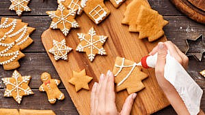 Photo of someone using royal icing to ice gingerbread cookies