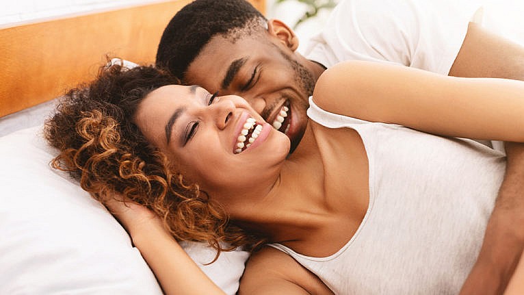 Photo of a couple laughing and cuddling in bed